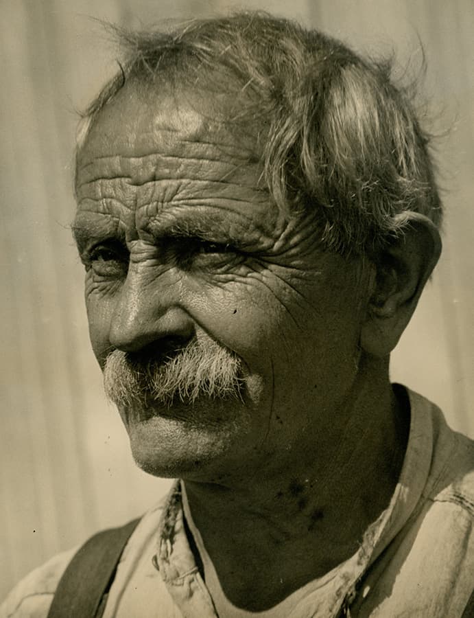 Portrait of an older man with a mustache and weathered face.