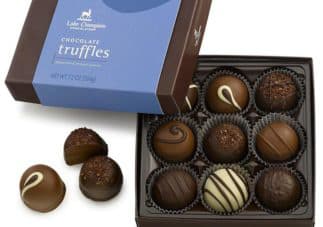 A box of assorted chocolate truffles with a few pieces placed beside it.