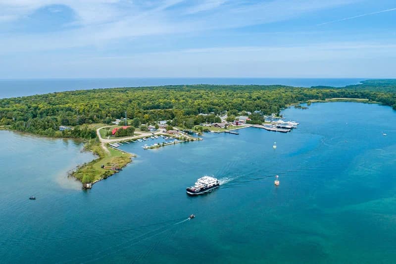 Aerial view of a lush green island with a marina and a boat navigating the blue waters. Aerial view of a lush green island with a marina and a boat navigating the blue waters.