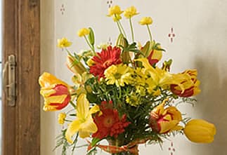 A vibrant bouquet of yellow, red, and orange flowers in a glass vase.